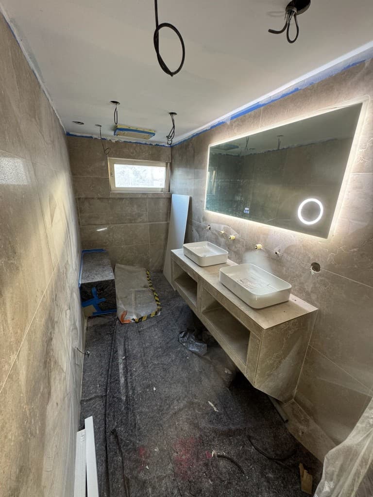 Salle de bain en cours de rénovation avec carrelage et miroir rétroéclairé